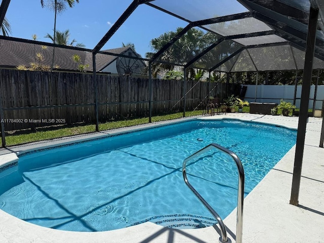view of swimming pool with a fenced backyard, a fenced in pool, and a lanai