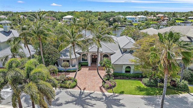 mediterranean / spanish-style house featuring a front yard, a tile roof, decorative driveway, and stucco siding