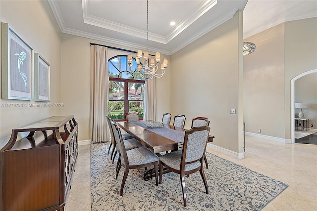 dining space with arched walkways, ornamental molding, a chandelier, a raised ceiling, and baseboards