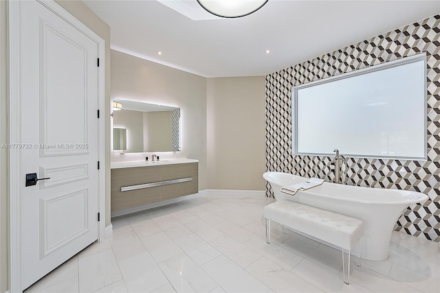 bathroom with a soaking tub, vanity, marble finish floor, tile walls, and baseboards