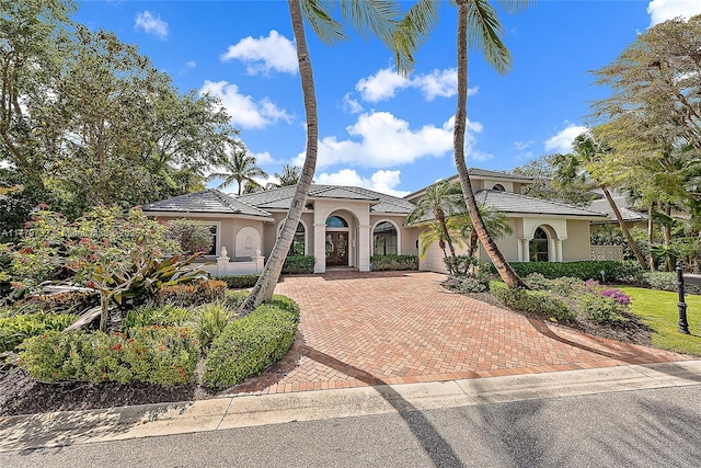mediterranean / spanish-style home featuring a garage, decorative driveway, and stucco siding
