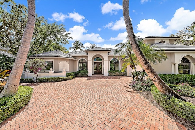 mediterranean / spanish home with a garage, stucco siding, a tiled roof, and decorative driveway