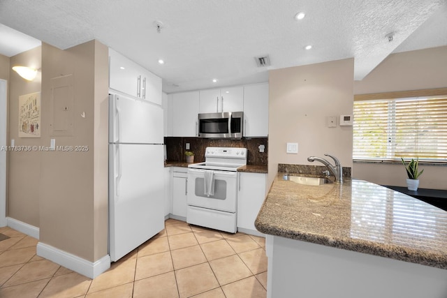 kitchen with visible vents, a sink, light tile patterned floors, a peninsula, and white appliances