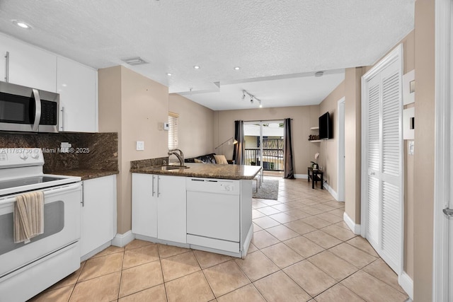 1918 Brickell Ave Unit 204, Miami, FL 33129 - kitchen with white appliances, a peninsula, open floor plan, white cabinetry, and dark countertops