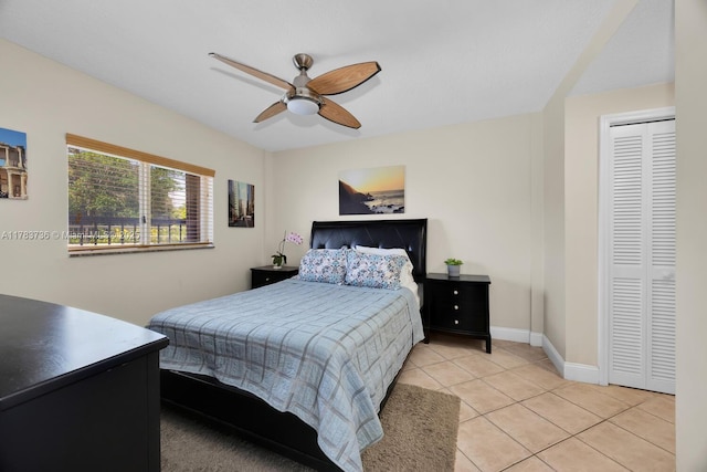 bedroom featuring light tile patterned flooring, baseboards, a ceiling fan, and a closet