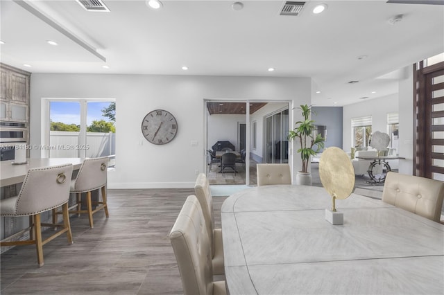 dining space featuring recessed lighting, wood finished floors, a healthy amount of sunlight, and visible vents