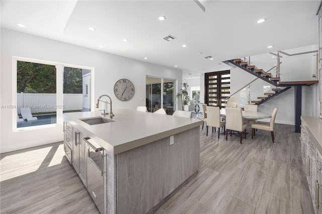 kitchen featuring a wealth of natural light, a sink, a center island with sink, and recessed lighting
