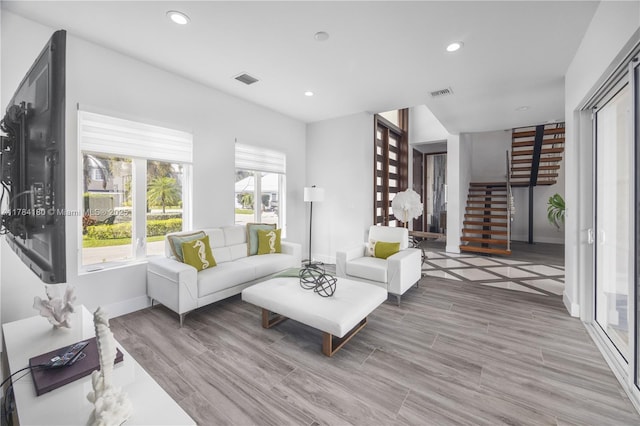living area featuring baseboards, stairs, visible vents, and recessed lighting