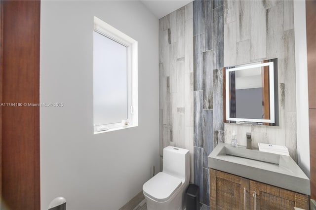bathroom with tile walls, toilet, and vanity