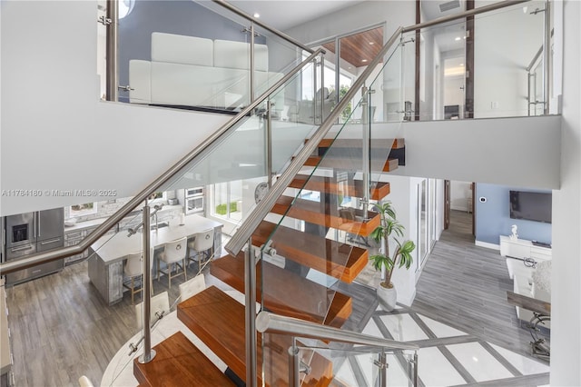 stairs featuring wood finished floors and recessed lighting