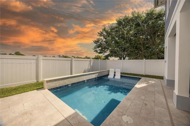 pool at dusk with a fenced backyard, a fenced in pool, and a patio
