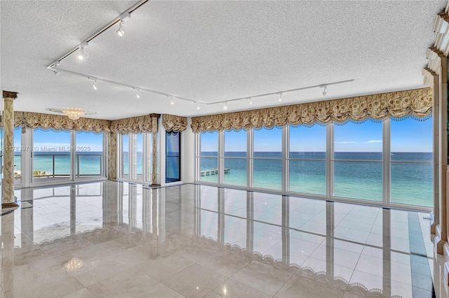 unfurnished sunroom featuring a water view and rail lighting