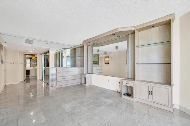 interior space featuring a textured ceiling, baseboards, visible vents, and marble finish floor