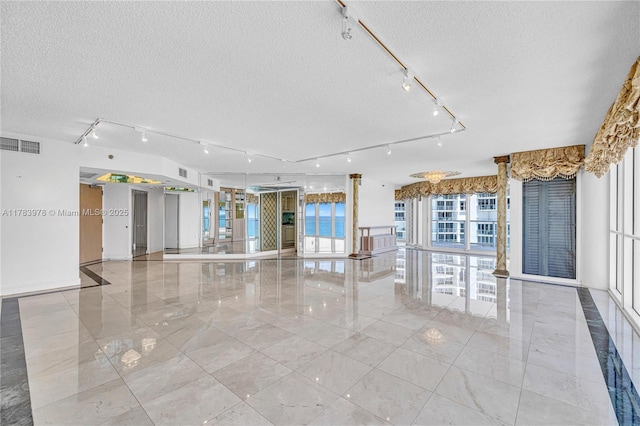 empty room featuring visible vents, rail lighting, a textured ceiling, and marble finish floor
