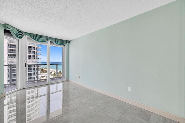 unfurnished room with a water view, a textured ceiling, and baseboards