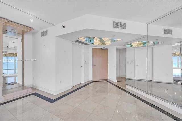 unfurnished room with a textured ceiling, baseboards, and visible vents