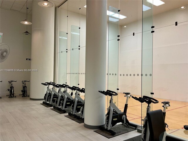 workout area featuring baseboards, wood finished floors, and a towering ceiling