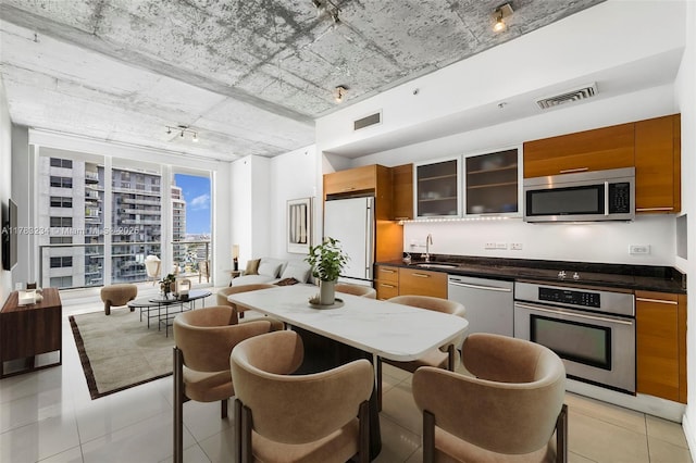 3470 E Coast Ave Unit H2706, Miami, FL 33137 - kitchen featuring stainless steel appliances, brown cabinets, light tile patterned flooring, glass insert cabinets, and dark countertops