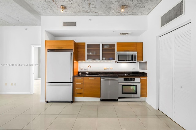 3470 E Coast Ave Unit H2706, Miami, FL 33137 - kitchen featuring stainless steel appliances, brown cabinetry, dark countertops, and glass insert cabinets