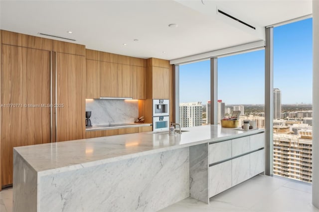 2000 S Ocean Dr Unit 28A, Hallandale Beach, FL 33009 - kitchen featuring backsplash, double oven, light stone counters, and modern cabinets