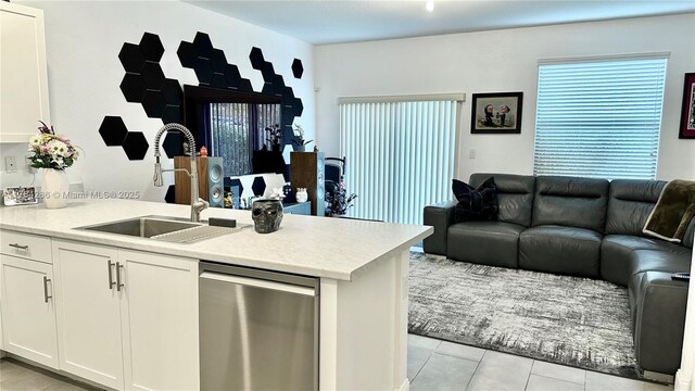 kitchen featuring white cabinets, light tile patterned flooring, a sink, light countertops, and open floor plan