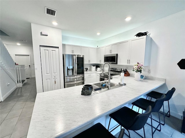 kitchen featuring visible vents, light countertops, appliances with stainless steel finishes, a peninsula, and a breakfast bar area