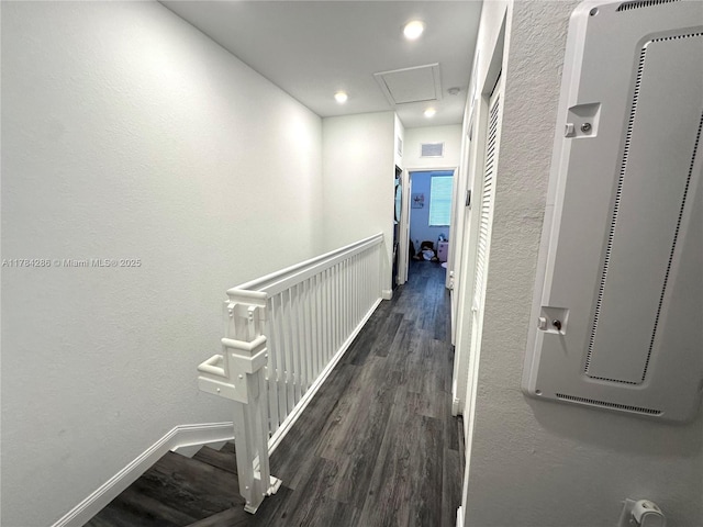 corridor featuring visible vents, wood finished floors, attic access, an upstairs landing, and a textured wall