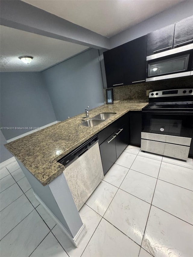 5955 NW 25th Ct Unit 208, Sunrise, FL 33313 - kitchen featuring stainless steel appliances, dark cabinetry, a peninsula, decorative backsplash, and dark stone counters