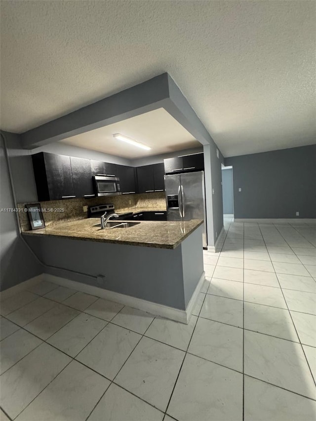 5955 NW 25th Ct Unit 208, Sunrise, FL 33313 - kitchen featuring appliances with stainless steel finishes, dark cabinetry, decorative backsplash, a peninsula, and dark stone counters