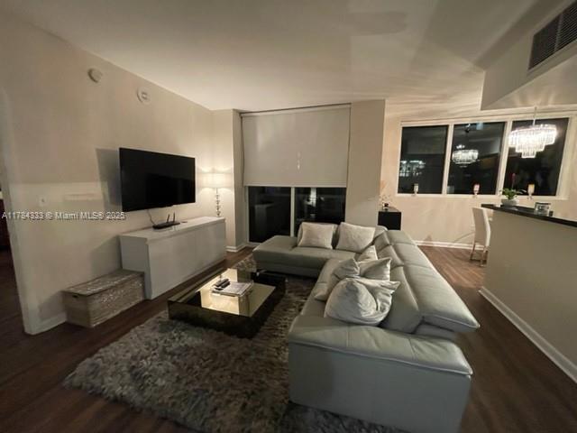 living area featuring visible vents, baseboards, and dark wood finished floors