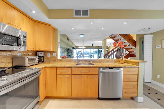 kitchen featuring a peninsula, visible vents, appliances with stainless steel finishes, a sink, and backsplash