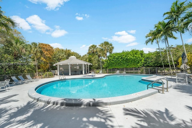 community pool with a gazebo, fence, and a patio