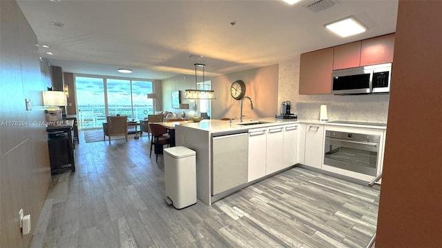 400 SE Sunny Isles Blvd Unit 1702, Sunny Isles Beach, FL 33160 - kitchen with black appliances, a sink, light wood finished floors, a peninsula, and light countertops