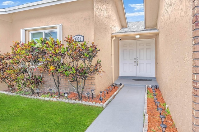 property entrance with a shingled roof and stucco siding