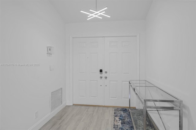 interior space featuring a notable chandelier, light wood-type flooring, visible vents, and baseboards