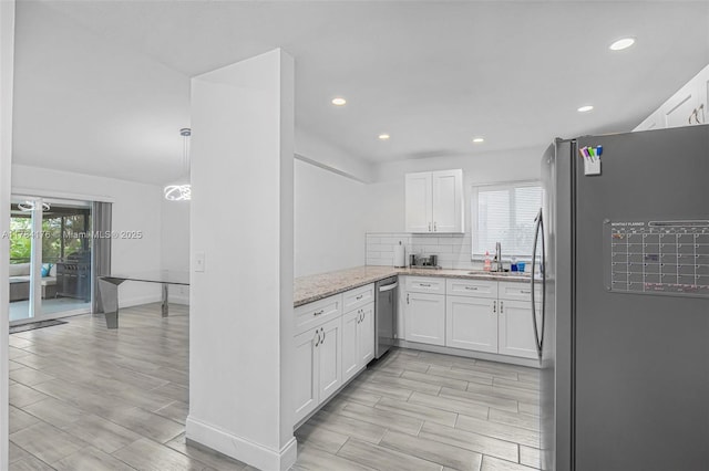 kitchen with white cabinets, light stone counters, a sink, wood tiled floor, and stainless steel appliances