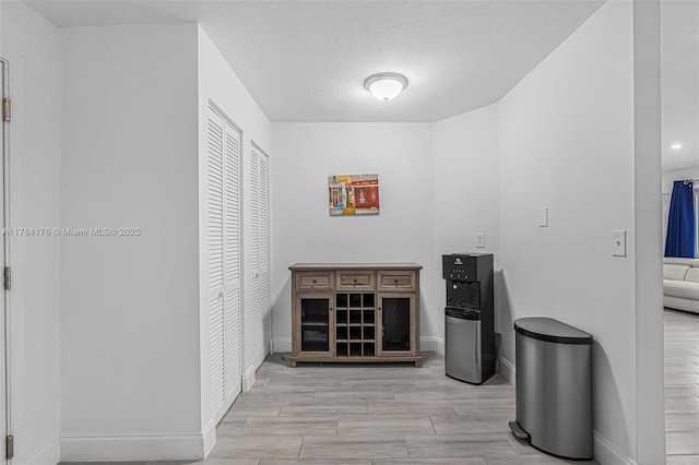 corridor featuring baseboards, a textured ceiling, and wood finished floors