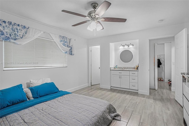 bedroom with baseboards, a ceiling fan, connected bathroom, and light wood-style floors