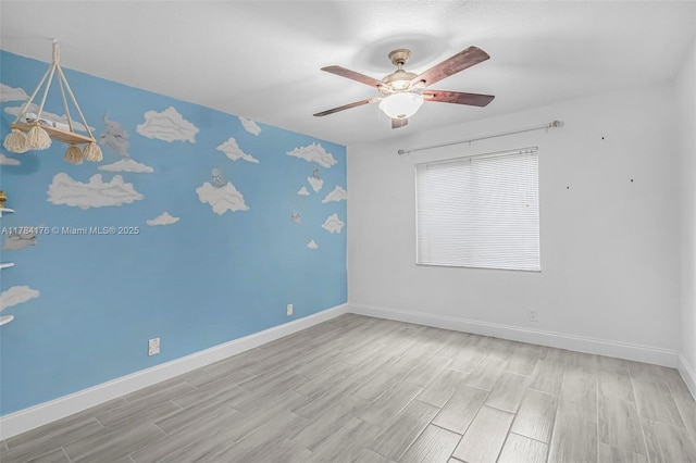spare room with ceiling fan, baseboards, and wood finished floors