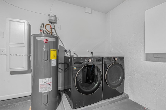 clothes washing area featuring electric water heater, a textured wall, washer and dryer, and laundry area