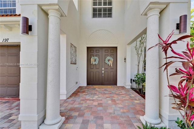doorway to property with a garage and stucco siding