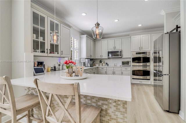 kitchen featuring a peninsula, crown molding, glass insert cabinets, and stainless steel appliances