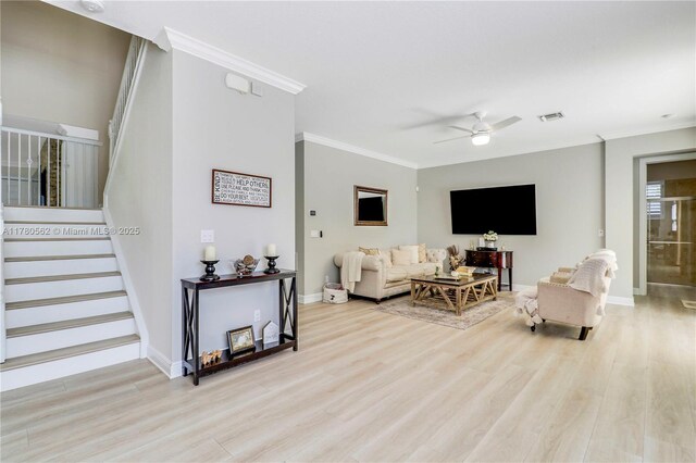 living room with crown molding, ceiling fan, visible vents, stairway, and wood finished floors