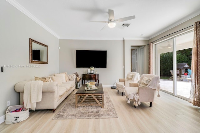 living area featuring baseboards, a ceiling fan, ornamental molding, and wood finished floors