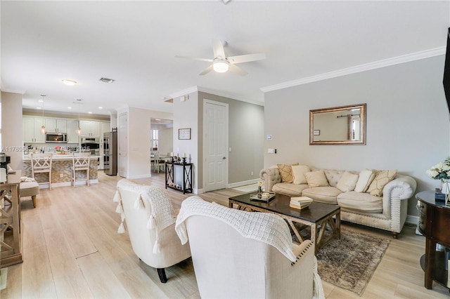 living room with light wood-style floors, crown molding, a ceiling fan, and baseboards
