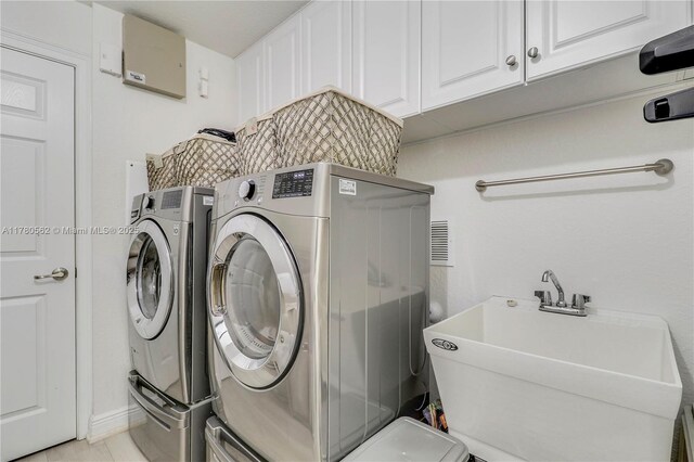 clothes washing area featuring a sink, cabinet space, and washer and clothes dryer