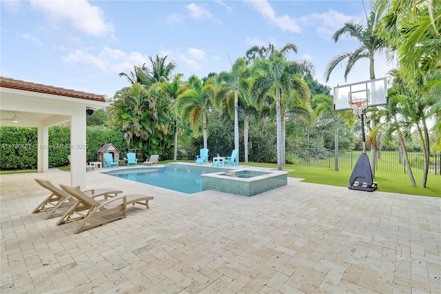 view of swimming pool featuring a patio area, a pool with connected hot tub, a lawn, fence, and an outbuilding