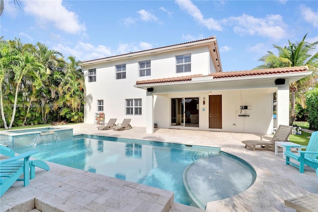 rear view of house featuring a patio, a tiled roof, a pool with connected hot tub, and stucco siding
