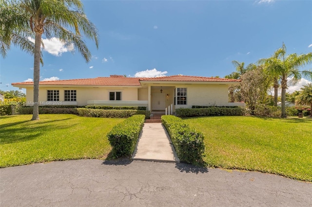 ranch-style home featuring a tiled roof, a front lawn, and stucco siding