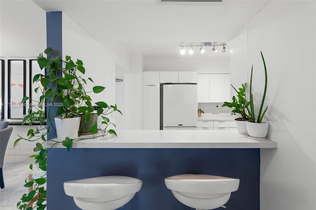 1500 Bay Rd Unit 668S, Miami Beach, FL 33139 - kitchen with a peninsula, white fridge, white cabinetry, and light countertops